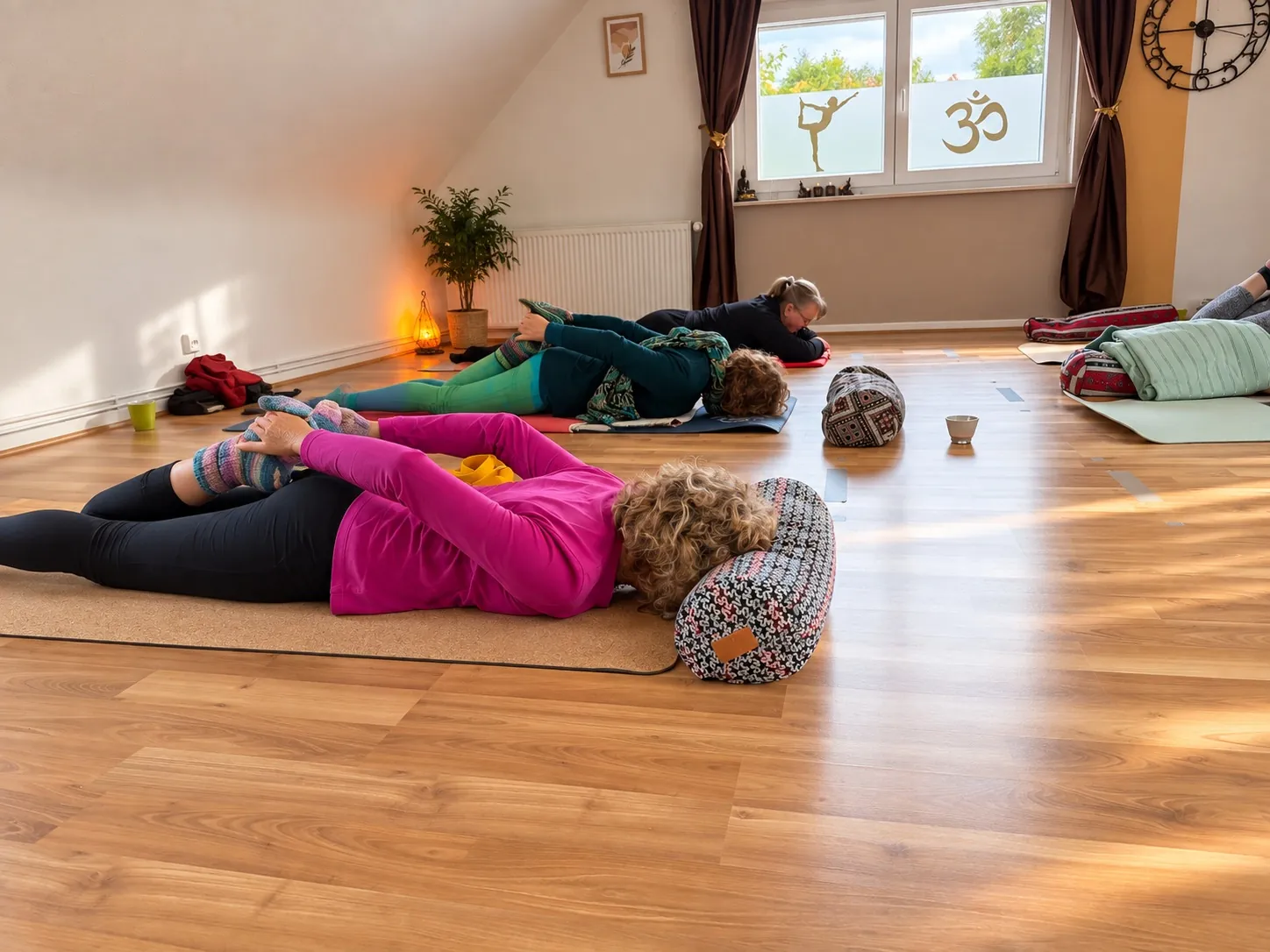 Teilnehmende entspannen auf Yogamatten mit Kissen und Decken